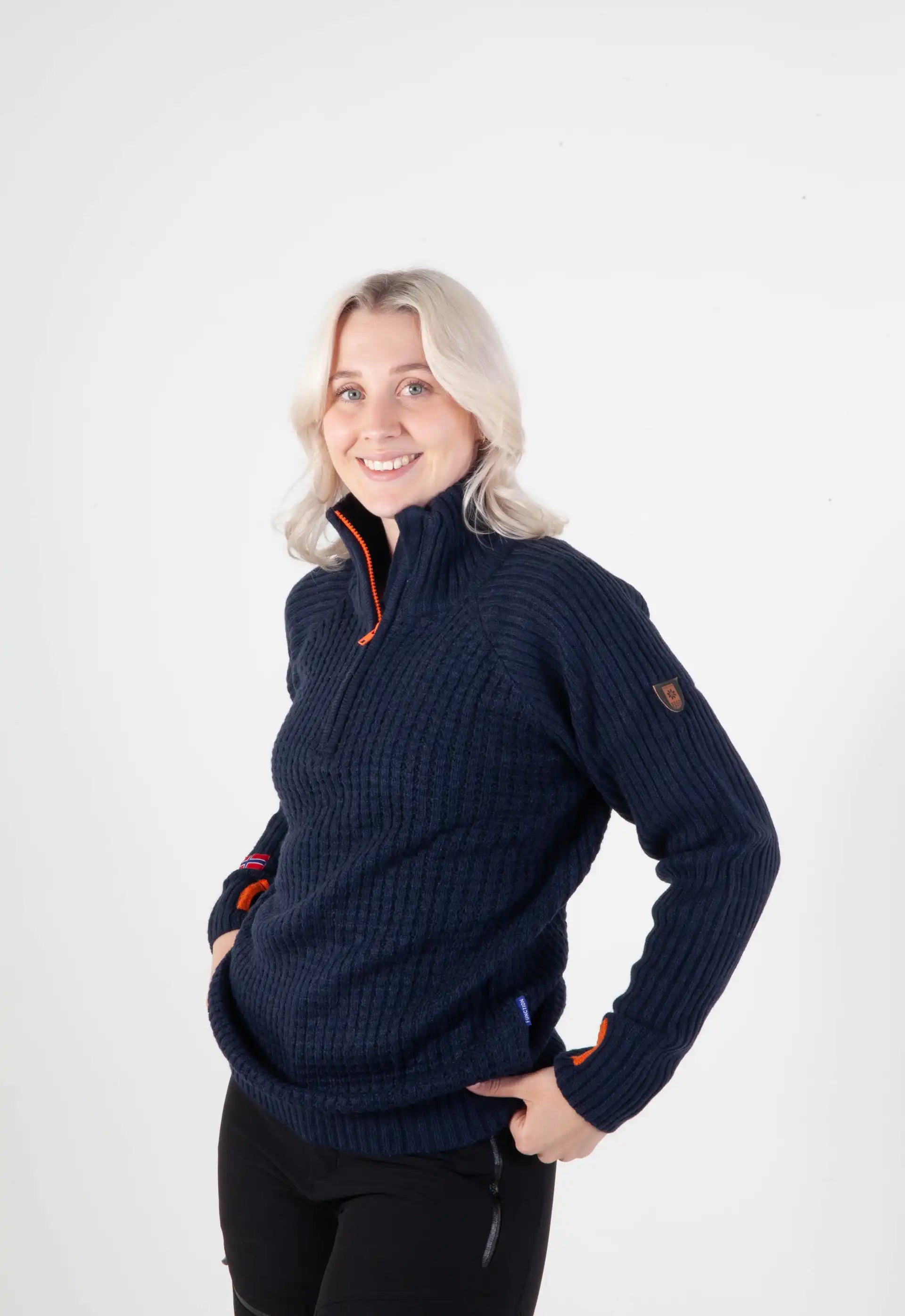 Ullgenser Villmark i blå og orange med høy hals og glidelås, tommelhull for komfort, laget av slitesterk ullblanding, perfekt for friluftsliv og hverdagsbruk.