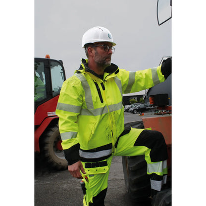 Lyngsøe Rainwear bukse i 4-veis stretch hi-vis gul/sort, designet for komfort og synlighet i krevende arbeidsforhold, med elastisk midje, avtagbare skulderstropper, pustende og vanntett materiale, perfekt for all slags vær.